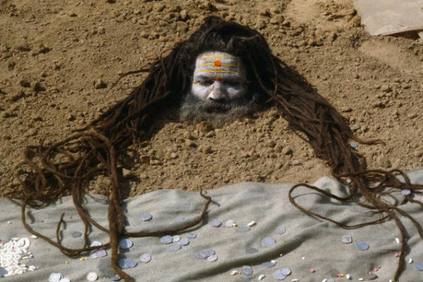 A sadhu buries his body in sand during a solar eclipse ceremony in Kurukhshtra